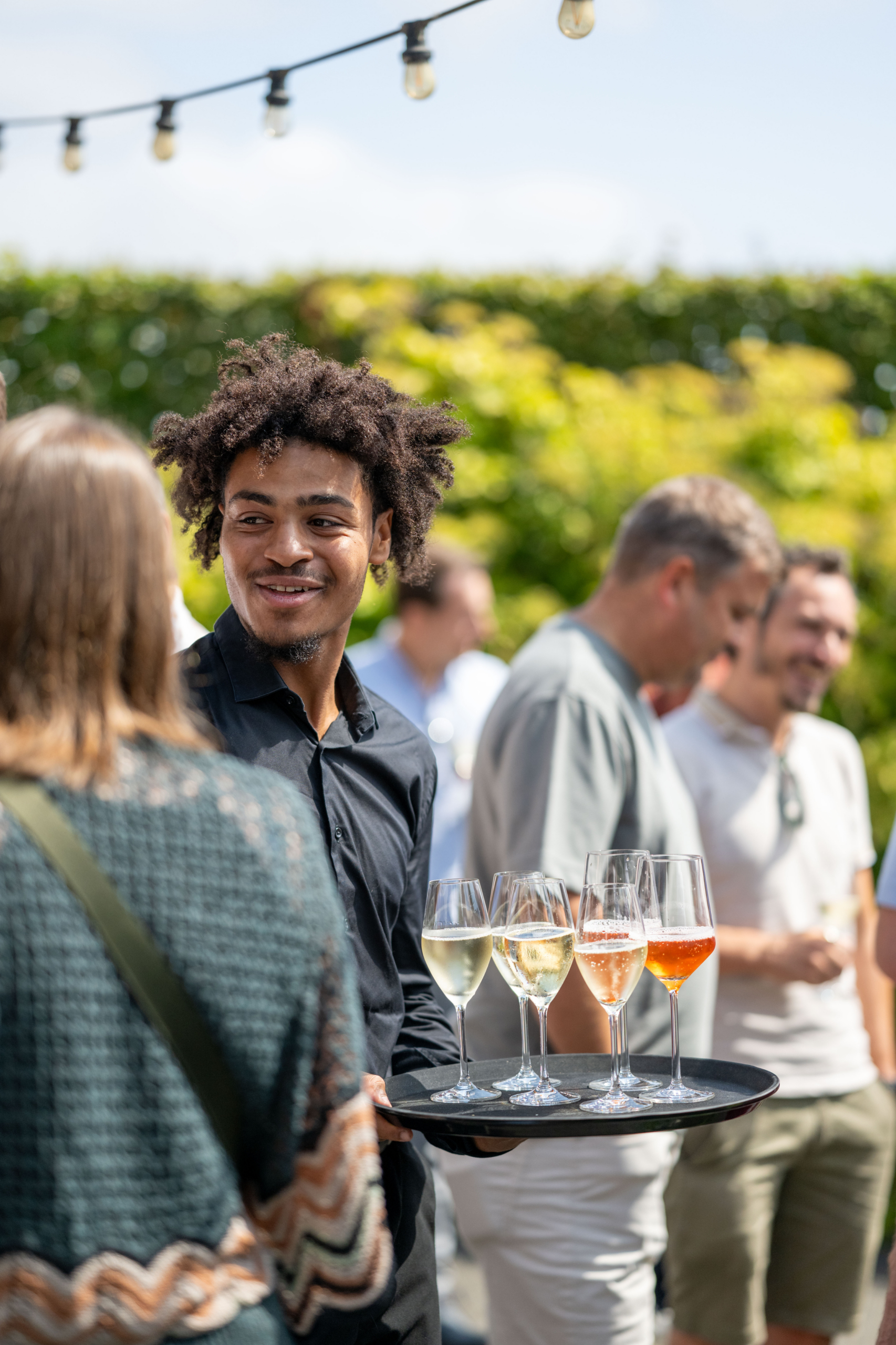 Collega’s praten bij op een tuinfeest terwijl drankjes worden rondgebracht