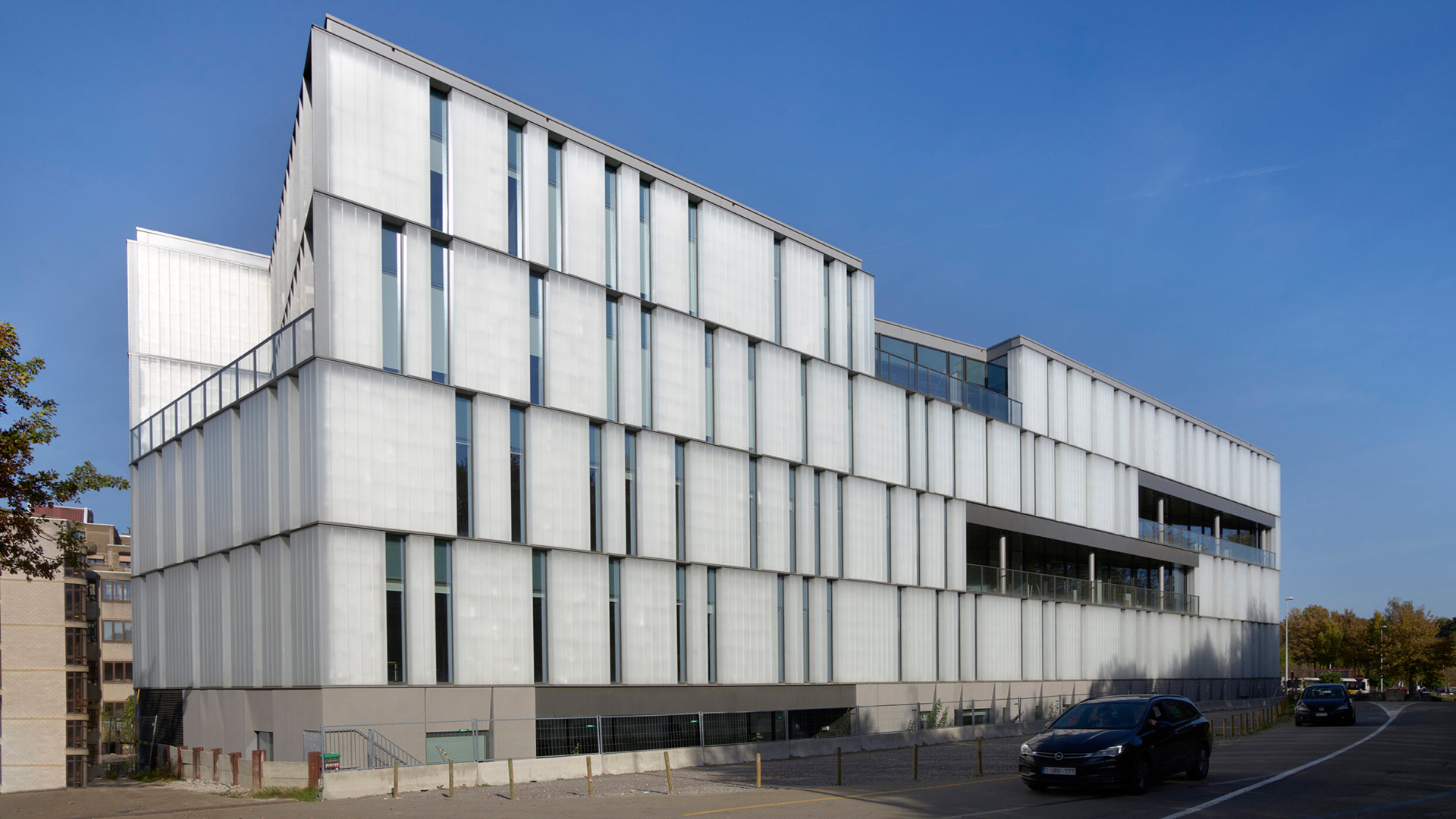 Wit gebouw van vier bouwlagen met een gevel van verticale lamellen