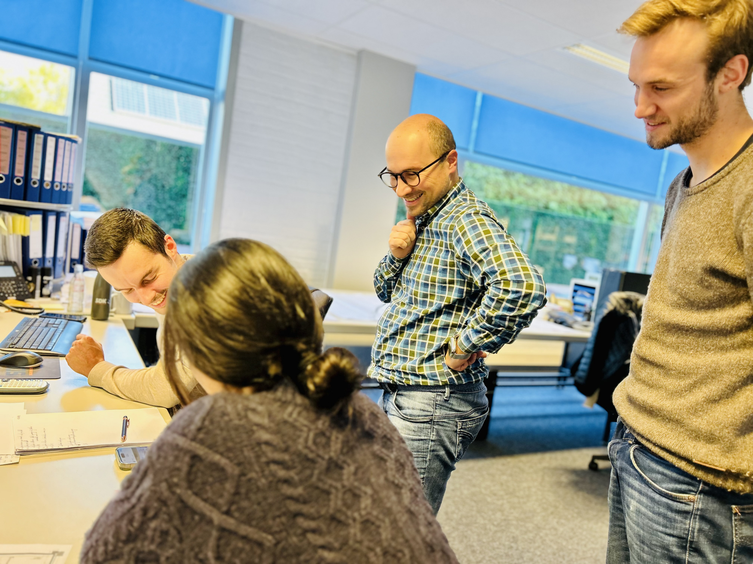 Vier collega’s overleggen aan een bureau