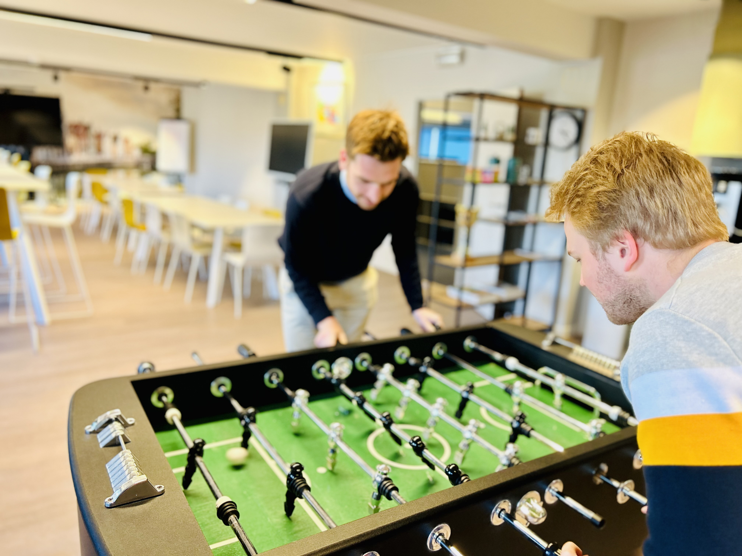 Twee collega’s spelen tafelvoetbal in de kantine