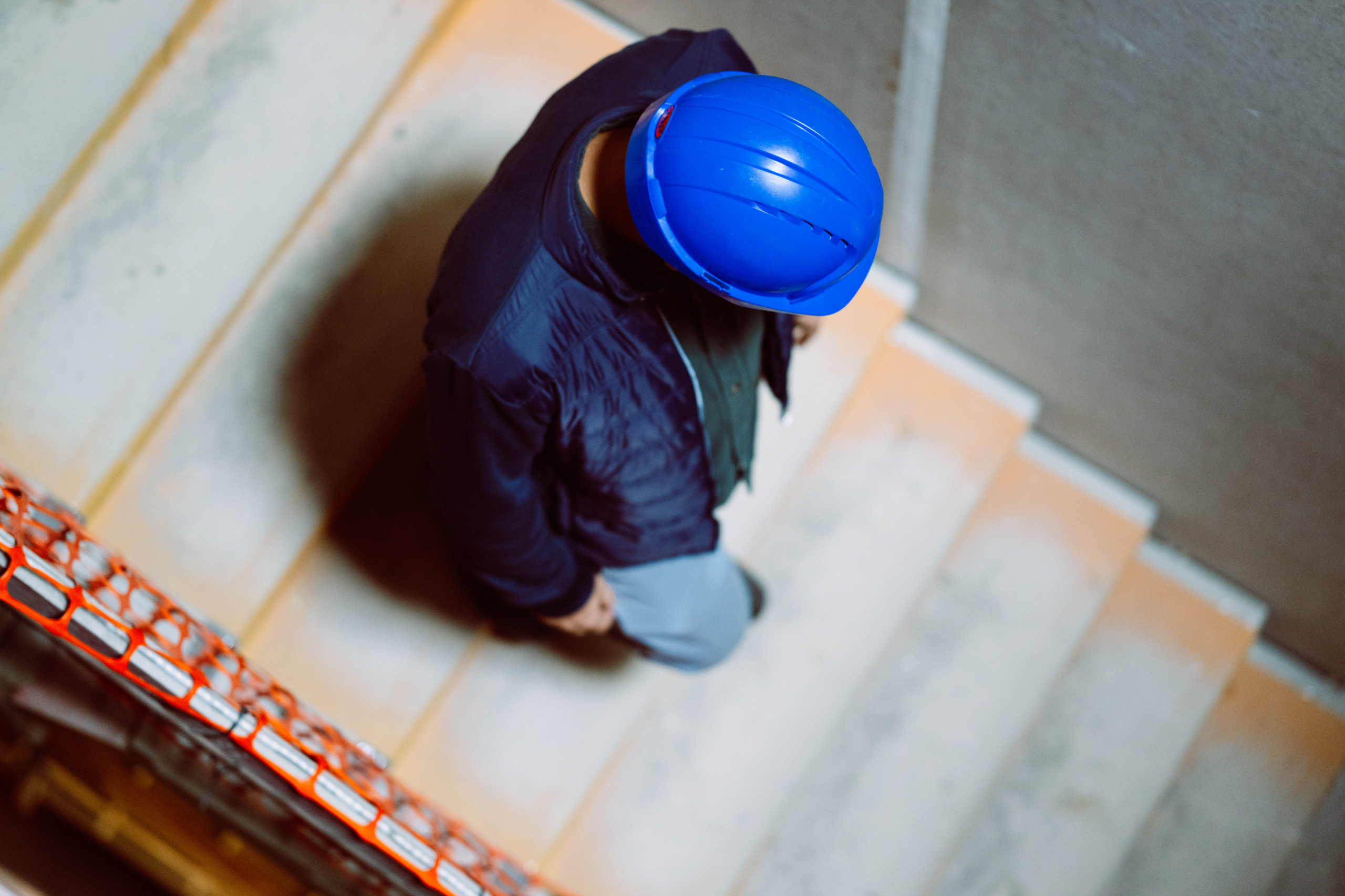 Bovenaanzicht van een ingenieur met blauwe helm op een betonnen trap