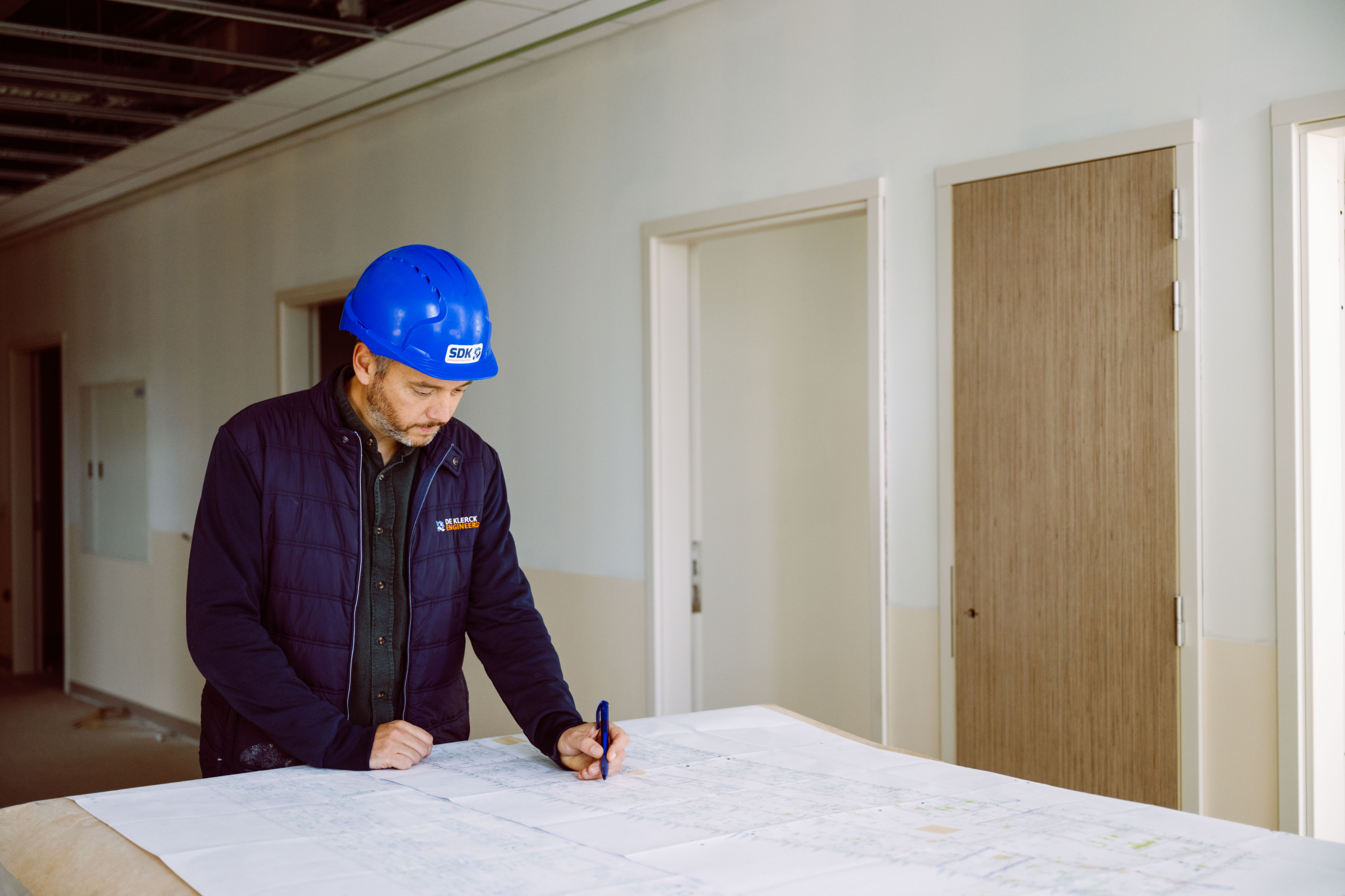 Ingenieur noteert op een bouwplan op de werf