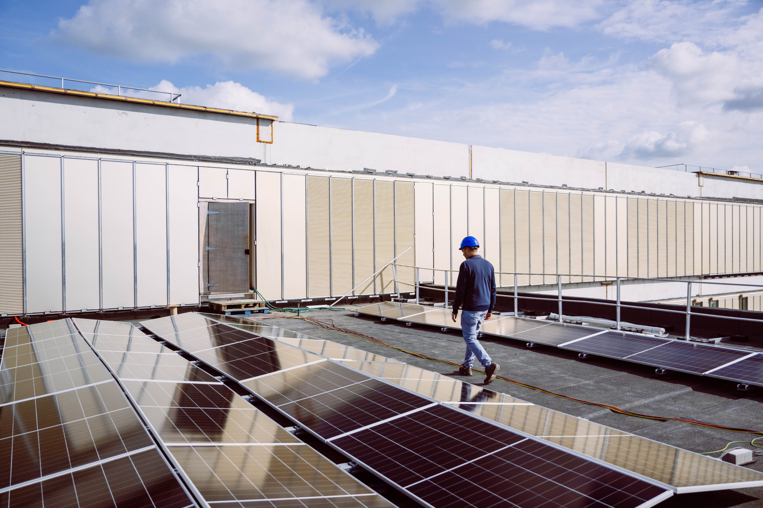 Ingenieur loopt langs zonnepanelen op een plat dak
