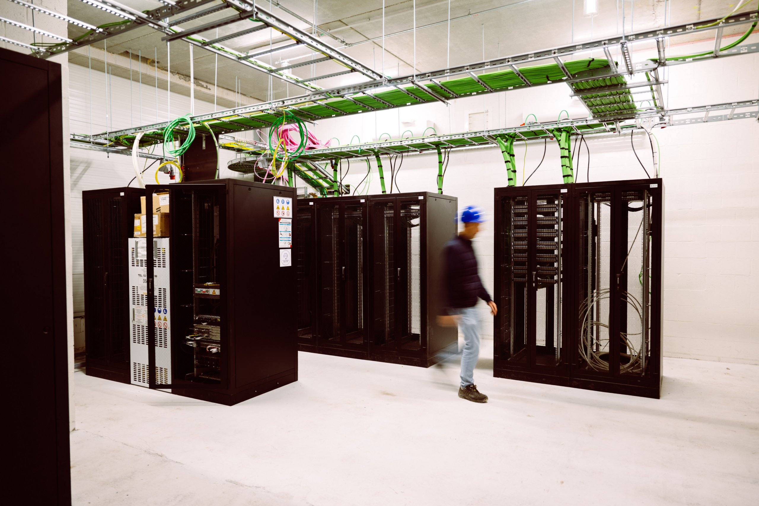 Serverruimte met zwarte racks en groene kabelgoten